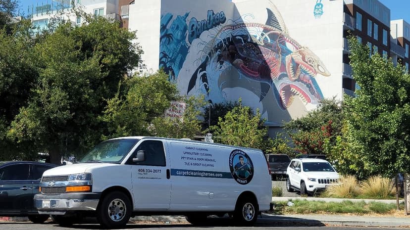 White service van parked in front of a colorful shark mural on a city building.